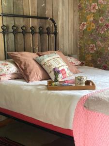 a bed with a tray with a cup and pillows at The Old Apple Shed cosy heated cottage in a meadow close to the charming village of Bethersden in Ashford