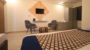 a bedroom with a bed and two chairs and a tv at Hushvan Resorts in Devaprayāg
