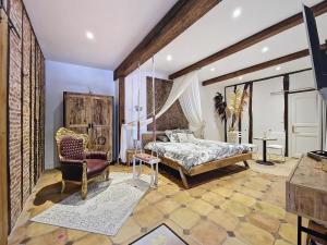 a bedroom with a bed and a chair at LE PRIEURE - Suites romantiques spa privatif, piscine, jardin, massages proche de Toulouse in Verfeil +43 photos
