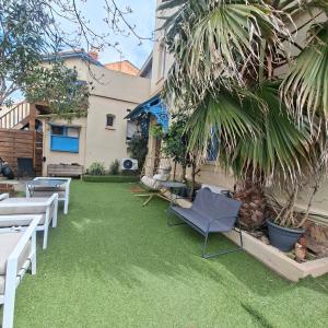 a lawn with chairs and a palm tree in a yard at Hôtel Le Chalet in Valras-Plage