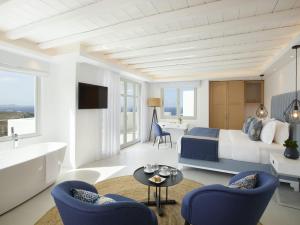 a hotel room with a bed and a tub and a sink at Epic Blue Mykonos in Houlakia