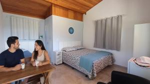 a man and woman sitting at a table in a bedroom at Chalé inteiro Canto da Graúna in Ibicoara