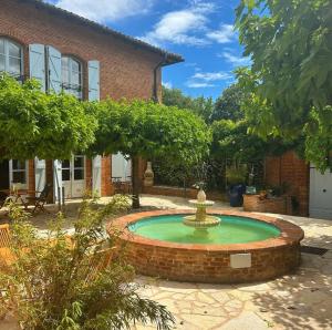 a fountain in the courtyard of a house at LE PRIEURE - Suites romantiques spa privatif, piscine, jardin, massages proche de Toulouse in Verfeil