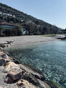 a body of water with rocks and houses in the background at Camping Baldo in Brenzone sul Garda +36 photos