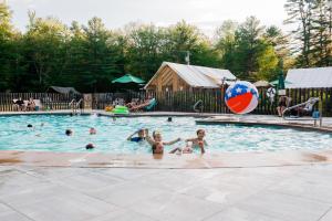 a group of people in a swimming pool with a beach ball at Huttopia White Mountains in Albany