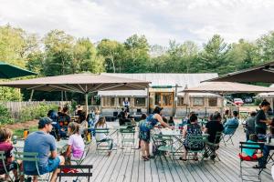 a group of people sitting at tables in a patio at Huttopia White Mountains in Albany