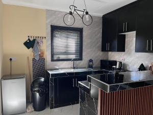 a kitchen with black cabinets and a sink at Sedudu Turn Cottages in Maun