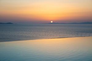 a sunset over the ocean with the sun in the distance at Epic Blue Mykonos in Houlakia +62 photos