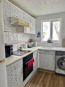 a kitchen with white cabinets and a sink at Juniper Apartment - 2 Bedroom in Goodmayes
