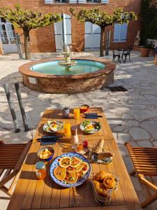 a picnic table with food on it next to a fountain at LE PRIEURE - Suites romantiques spa privatif, piscine, jardin, massages proche de Toulouse in Verfeil