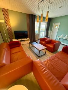 a living room with orange furniture and a television at Die Schlafstube - Apartments und mehr in Neuharlingersiel