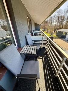 a porch with two benches and a table on a balcony at Die Schlafstube - Apartments und mehr in Neuharlingersiel