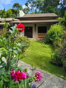 a garden with pink flowers in front of a house at Pousada Medeiros in Monte Verde +193 photos