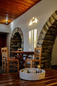 a room with a table and chairs and a stone wall at Anéza house tinos in Skaládhos