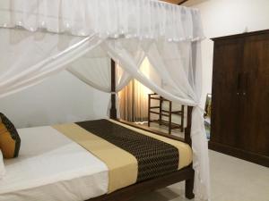 a bedroom with a canopy bed with white curtains at GG Lodge Mirissa in Mirissa +44 photos