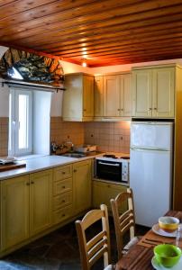 a kitchen with yellow cabinets and a white refrigerator at Anéza house tinos in Skaládhos