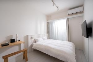 a white bedroom with a bed and a television at stella stay in Imari