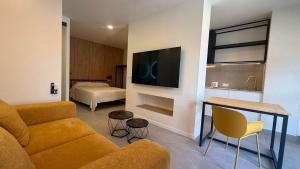 a living room with a couch and a tv and a bed at Bormujos Suites Sevilla in Bormujos