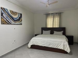a bedroom with a bed and a painting on the wall at ENA Apartments in Apenkwa