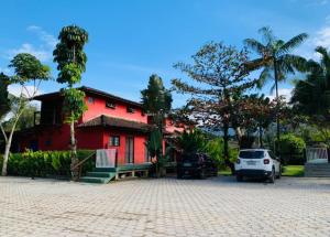 a red house with cars parked in front of it at Chales Terra Pura in Camburi
