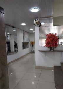 a hallway with a mirror and a vase of red flowers at Hotel Pampulha Palace in Belo Horizonte +35 photos