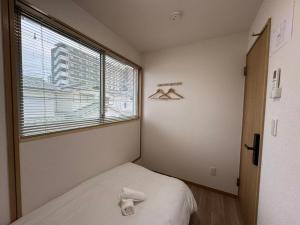 a small bedroom with a bed and a window at KIX Nest in Izumi-Sano