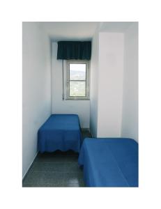 a small room with two beds and a window at B&B Corte degli Ulivi in Mattinata