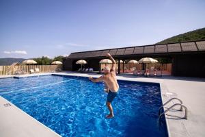 a man is jumping into a swimming pool at Huttopia Berkshires in Hancock