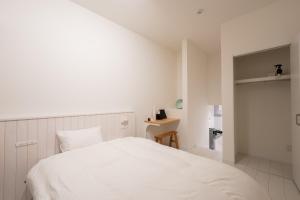 a white bedroom with a bed and a desk at stella stay in Imari
