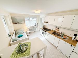 a kitchen with white cabinets and a table at Ferienwohnung Marie - WLAN, Küche, im Ortskern, Einkaufsläden in der Nähe in Malterdingen