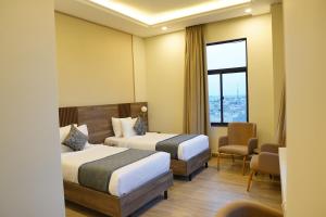 a hotel room with two beds and a chair at RT Serene Hotel - Larkana in Lāhori