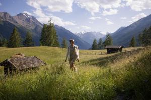 a man walking in a field with mountains in the background at Schönherr Haus in Neustift im Stubaital
