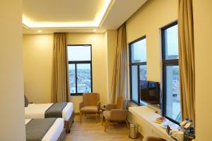 a hotel room with two beds and a tv and windows at RT Serene Hotel - Larkana in Lāhori