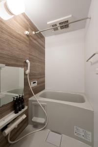 a bathroom with a bathtub with a hose hanging from the ceiling at stella stay in Imari +17 photos