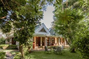 a house with chairs and a table in the yard at Tuli House in Harare