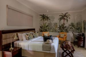 a bedroom with a large white bed and palm trees at Tuli House in Harare
