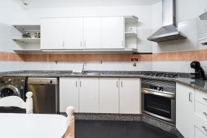 a kitchen with white cabinets and a sink at GuestReady - Charming Apartment with Ocean Views in Caniço
