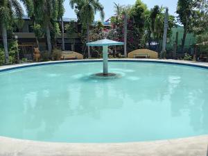 a large pool of water with a umbrella in it at Verde Royale Resort in Calasiao