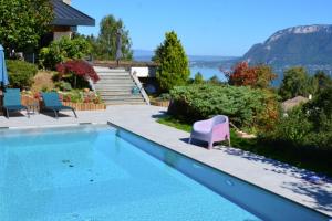 a swimming pool with chairs and a house at Le Panorama du Lac in Sévrier