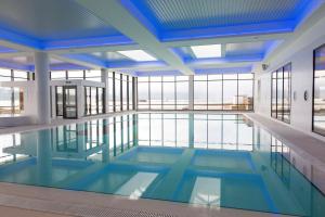 a large swimming pool with blue ceilings and windows at High Beach Cottage in Kames