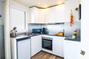 a white kitchen with white cabinets and a sink at La Loge de la Tour in Calais