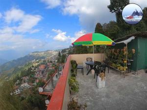 a patio with a table and a colorful umbrella at Laskus Homestay in Darjeeling