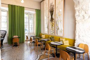 a restaurant with green curtains and tables and chairs at Le Cloître in Arles