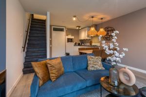 a living room with a blue couch and a kitchen at Welcome in - Appartement aan de duinen met balkon I Duinweg 18, Zoutelande 'Duinroos' in Zoutelande