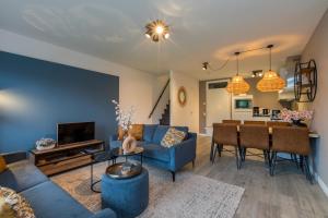 a living room with a blue couch and a table at Welcome in - Appartement aan de duinen met balkon I Duinweg 18, Zoutelande 'Duinroos' in Zoutelande