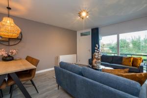 a living room with a blue couch and a table at Welcome in - Appartement aan de duinen met balkon I Duinweg 18, Zoutelande 'Duinroos' in Zoutelande +41 photos