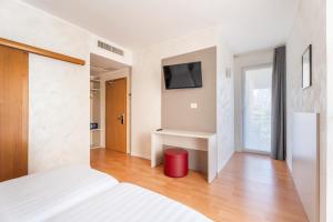ein Schlafzimmer mit einem Bett und einem Fernseher an der Wand in der Unterkunft Hotel Angelini in Nago-Torbole