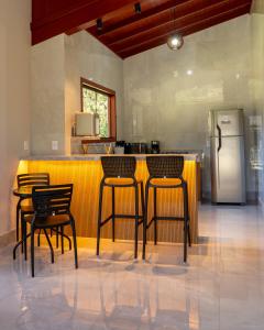 a kitchen with four chairs and a counter with a refrigerator at Chalé Estalagem Sítio Sossego in Domingos Martins