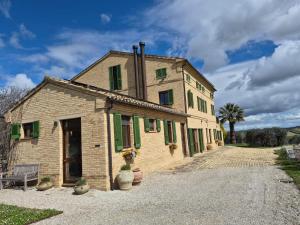 a stone building with green shutters on a road at Casal dei Fichi in Francavilla dʼEte