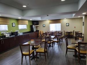 a restaurant with tables and chairs and a kitchen at Sleep Inn Richmond North in Richmond